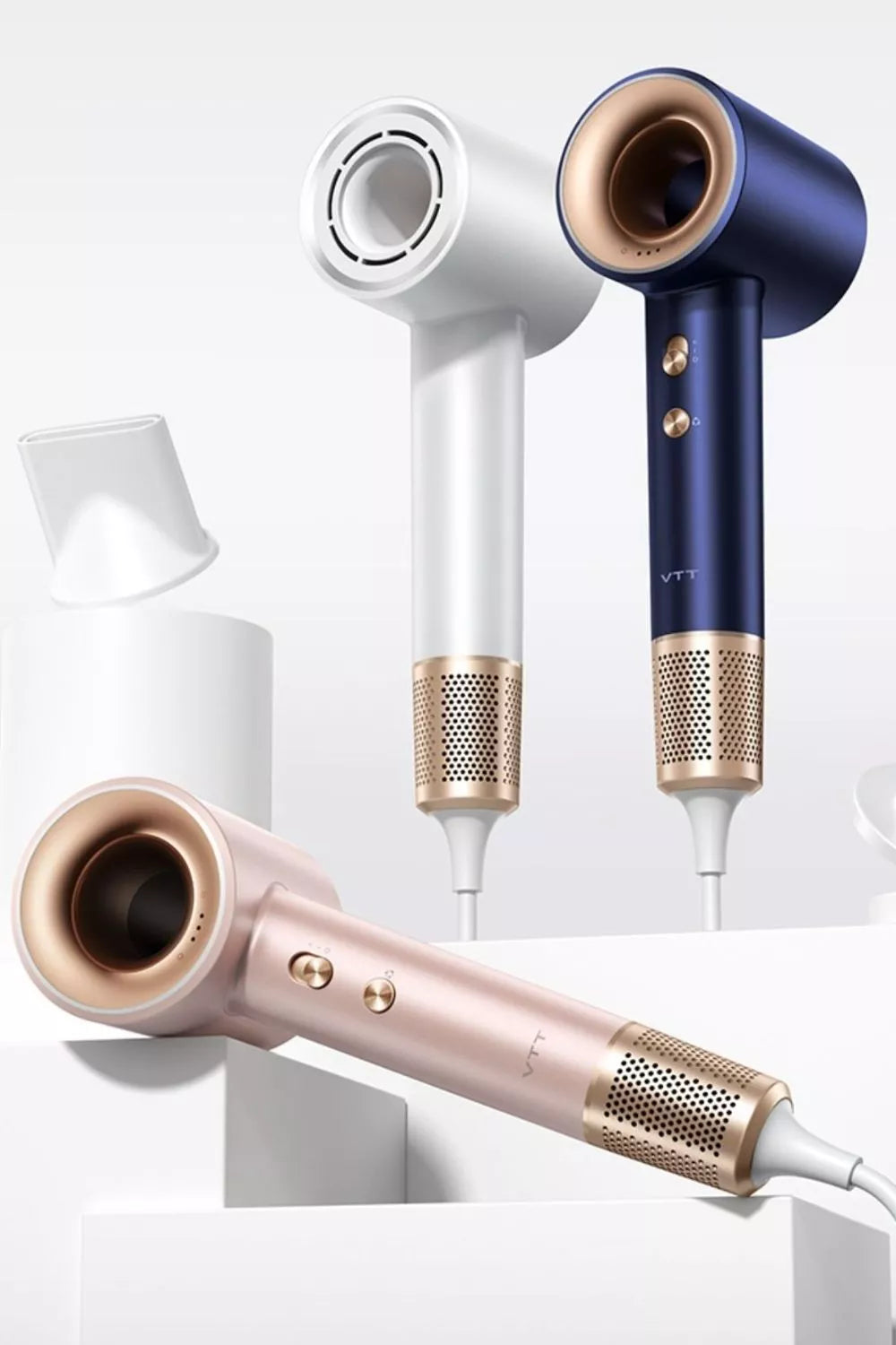 Three modern hair dryers in white, navy blue, and rose gold with metallic accents are displayed against a white background, standing upright with attachments nearby.