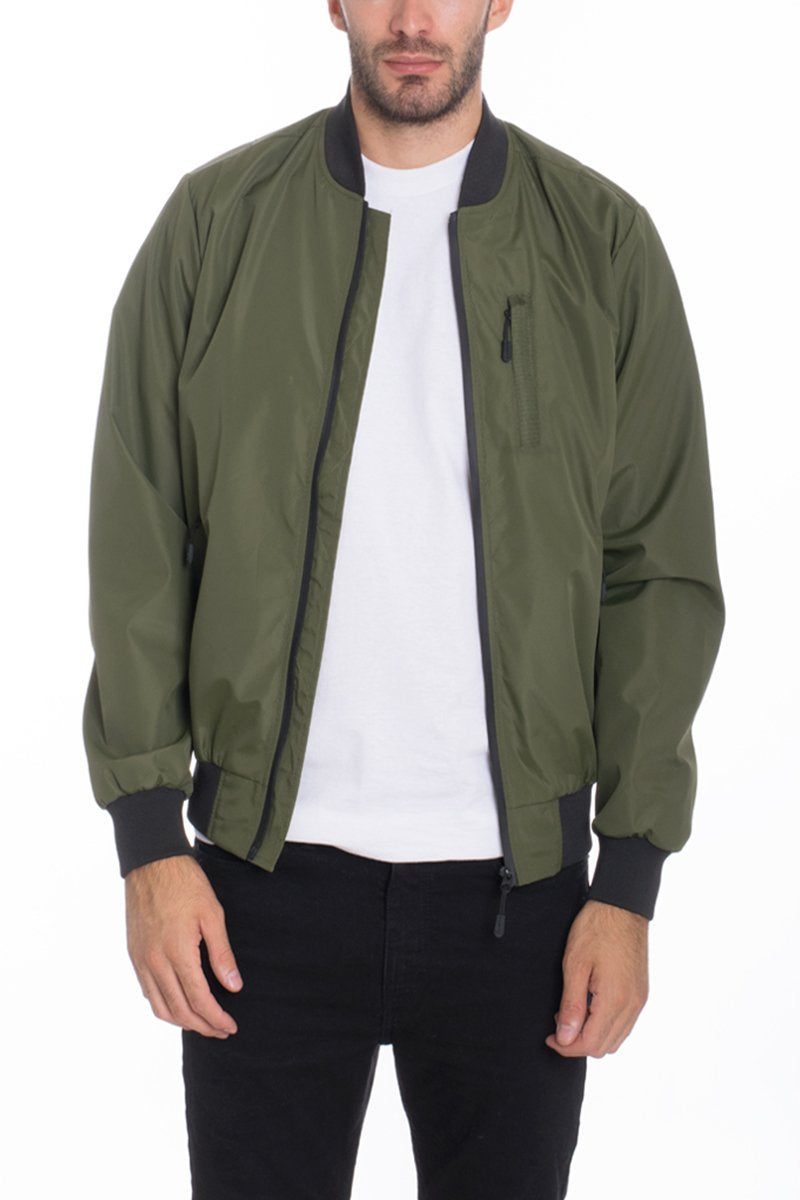 A person is wearing the Lime Milo Mens Vinyl Waterproof Windbreaker with black trim, paired with a white t-shirt and black pants, standing against a plain white background.