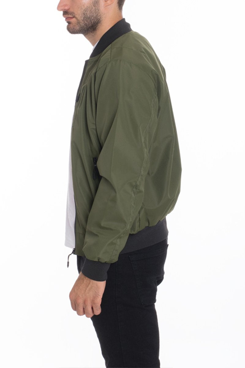 A man stands in profile against a white background, wearing the Lime Milo Mens Vinyl Waterproof Windbreaker in green over a white shirt and black pants.