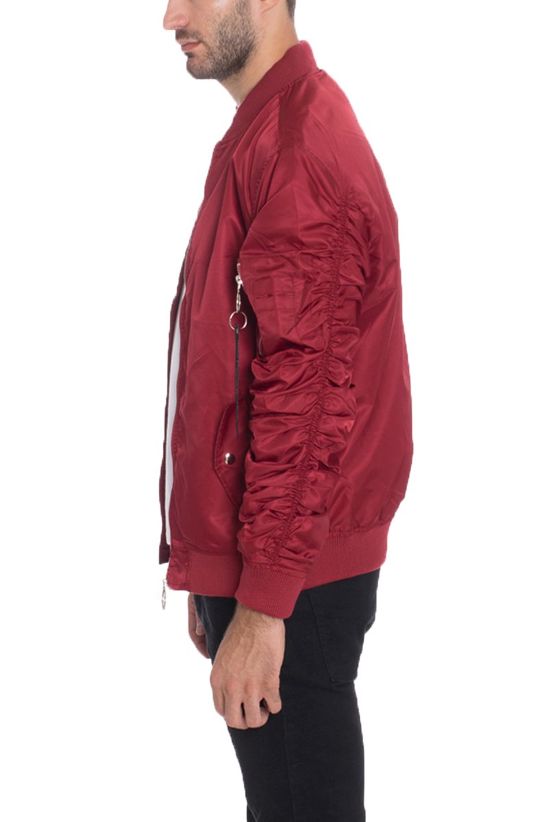 A man in profile wears the Lime Milo FLIGHT LINED BOMBER 6116—a shiny red jacket with scrunched sleeves and silver zippers, styled with black pants. This regular fit, machine washable bomber is designed for easy care.