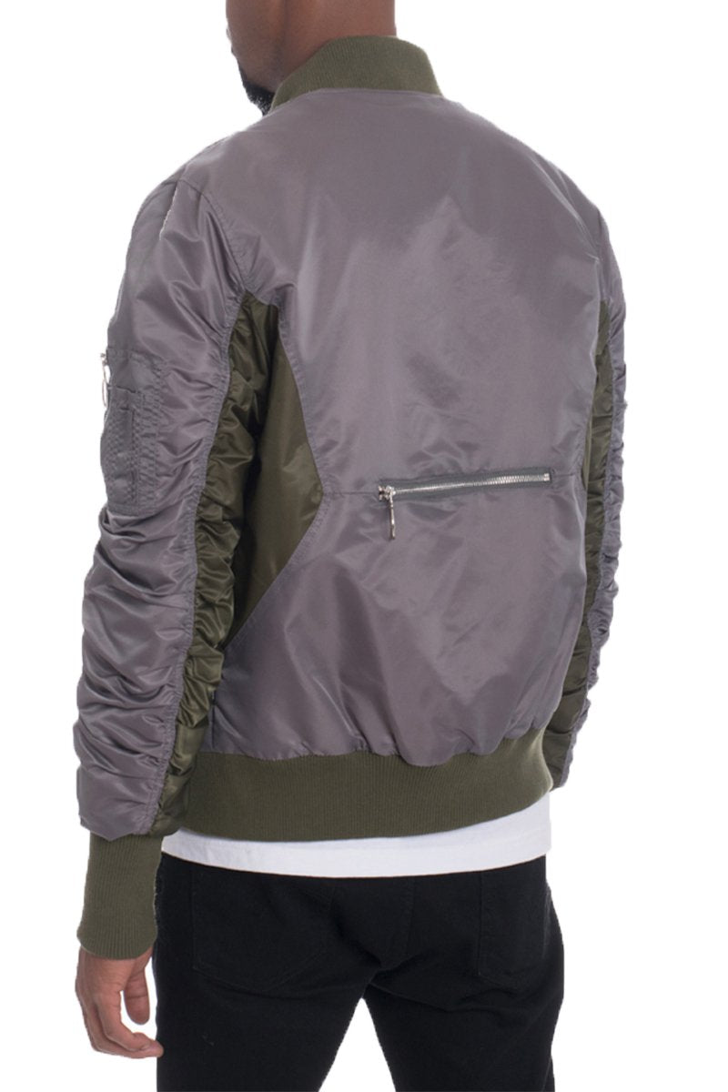 A person is shown from behind wearing Lime Milo's TWO TONE BOMBER, a regular fit jacket featuring shiny olive green and gray panels, scrunched sleeves, and a horizontal zipper pocket across the back.