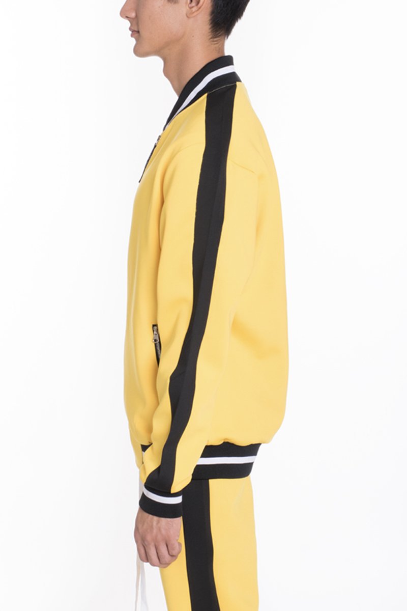 A person stands in profile against a white background wearing the Lime Milo Heavy Weight Solid Track Jacket in yellow with black sleeve stripes and matching yellow pants featuring black side stripes.