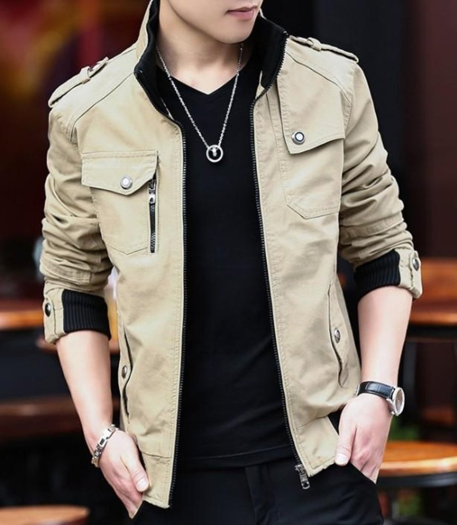 A person stands with hands in pockets, wearing the Yellow Pandora Mens Military Theme Short Jacket in beige over a black shirt, paired with a silver necklace, bracelet, and watch. The face is partially out of frame.